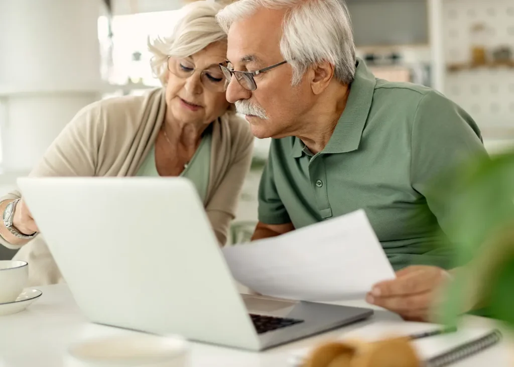 couple de personnes agees analysant leurs economies tout en parcourant les finances de la maison