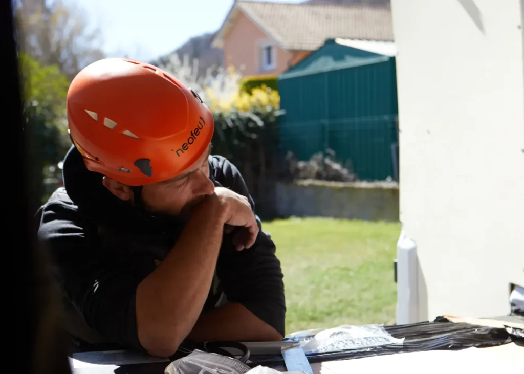 Un technicien solaire en pleine réflexion devant une maison, illustrant le calcul de la surface nécessaire de panneaux photovoltaïques