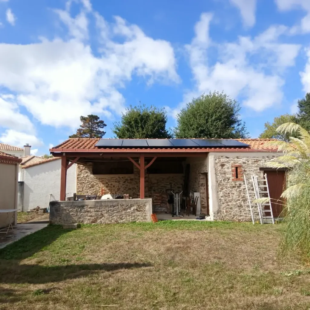 Panneaux solaires sur le toit d'une dépendance en pierre avec pergola à Bouaye, Loire-Atlantique
