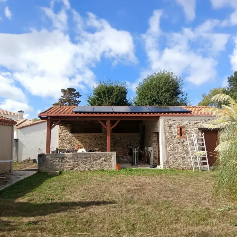 Panneaux solaires sur le toit d'une dépendance en pierre avec pergola à Bouaye, Loire-Atlantique