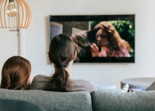Deux personnes regardant la télévision à la maison, confortablement installées grâce à une alimentation solaire